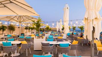 An outdoor dining area with tables and chairs, umbrellas, and string lights.
