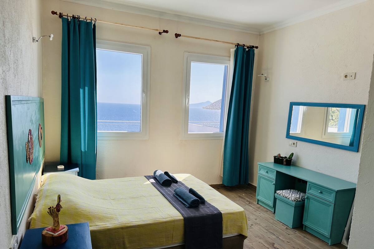A bedroom with two windows, a bed, a dresser, and a mirror.