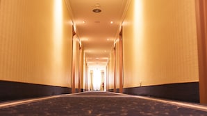 A hotel hallway with a carpeted floor, wooden walls, and a ceiling with recessed lighting. - Hotel Cap Polonio Pinneberg (Pinneberg)