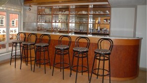 A bar area with a wooden counter and five metal bar stools. - Otel Akkoc (Isparta)