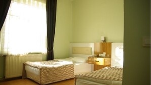 A room with two beds, a nightstand, a lamp, and a window with curtains. - Otel Akkoc (Isparta)