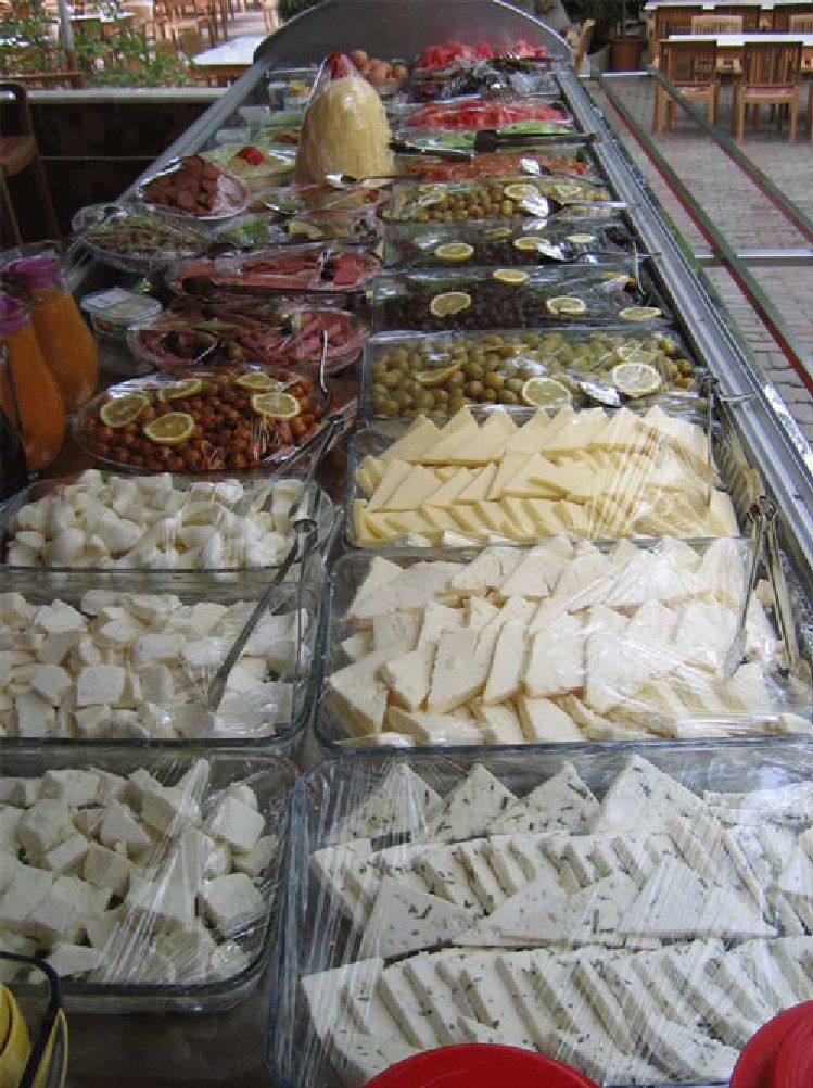 A deli counter with various cheeses, meats, and olives displayed in clear containers.