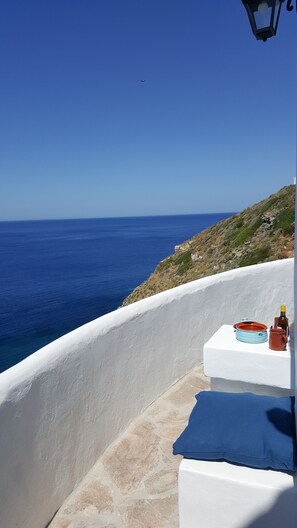 A white-walled building with a view of the sea and a distant airplane. - Aegean Eye Apartments (Sifnos)