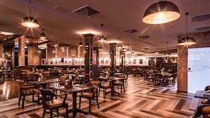 A spacious restaurant with multiple dining tables and chairs, large pendant lights, and a projection screen on the wall. - Hotel Diplomat (Zagreb)