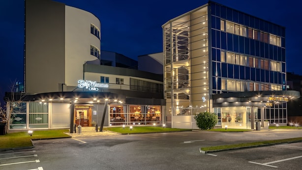 A hotel with a modern design, featuring a prominent glass facade and a well-lit entrance. - Hotel Diplomat (Zagreb)