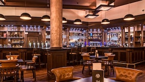 A bar area with wooden furniture, bar stools, and a variety of bottles and glasses on shelves. - Hotel Diplomat (Zagreb)