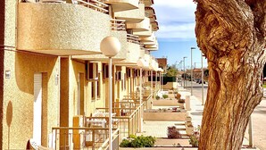 A building with multiple balconies, a tree in the foreground, and a clear sky. - Destinos de Sol Los Alcázares (Los Alcazares)