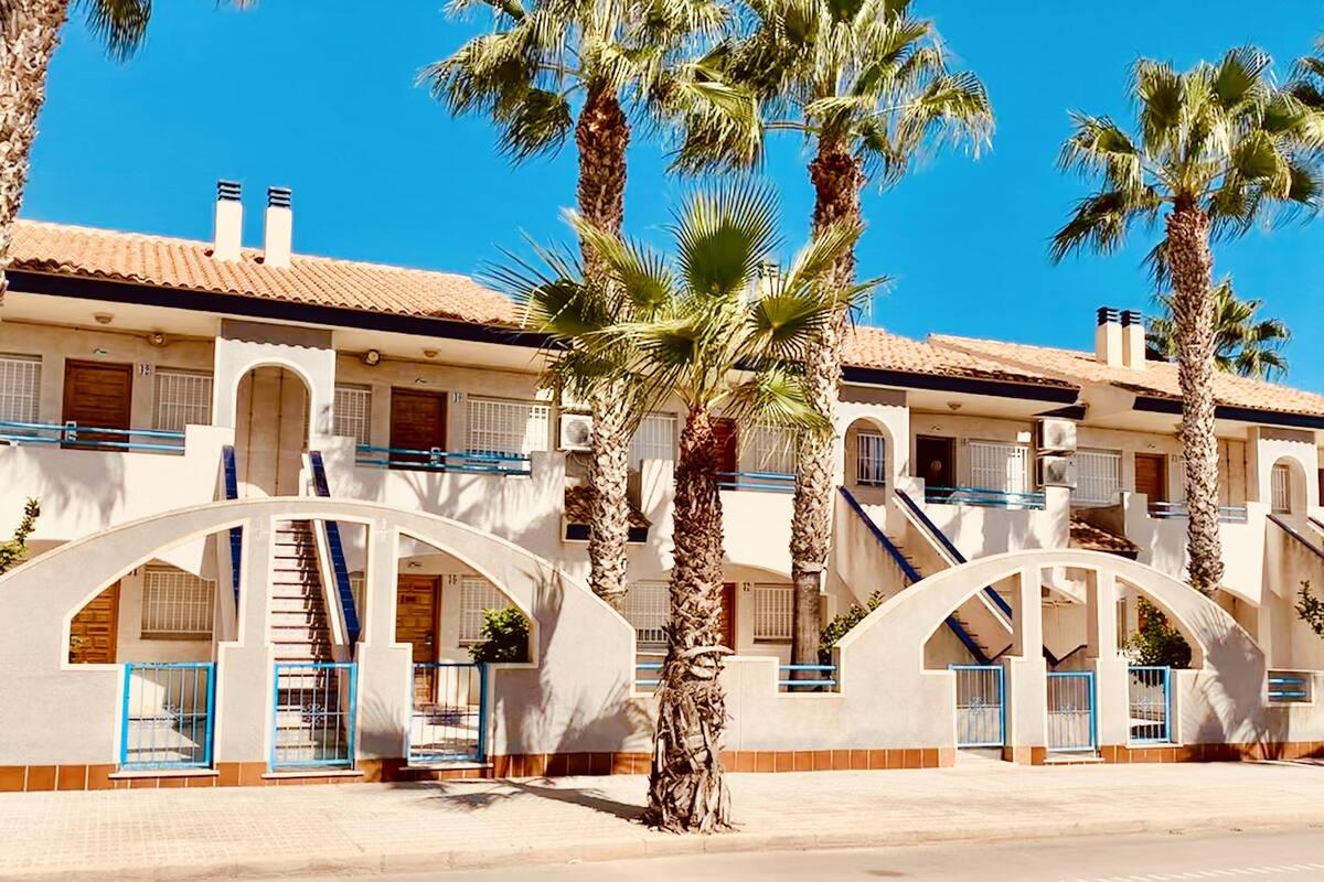Ein Hotel mit mehreren Stockwerken, Palmen und blauem Himmel.