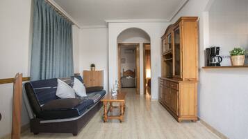Una sala de estar con un sofá, un mueble de madera y una cafetera.