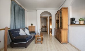 Una sala de estar con un sofá, un mueble de madera y una cafetera.
