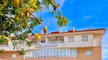 Un edificio de dos pisos con un cartel que dice 'Apartamentos Turísticos' y un restaurante 'Buffet'.