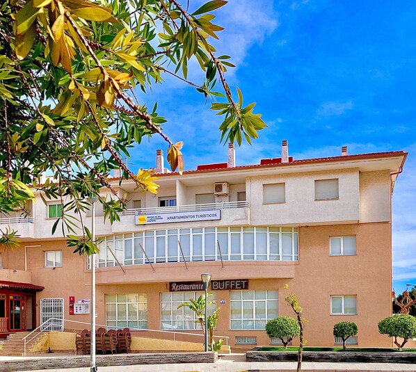 Un edificio de dos pisos con un cartel que dice 'Apartamentos Turísticos' y un restaurante 'Buffet'.