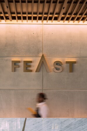 A sign with the word "FEAST" on a wall. - Hilton Port Moresby Hotel & Residences (Port Moresby)