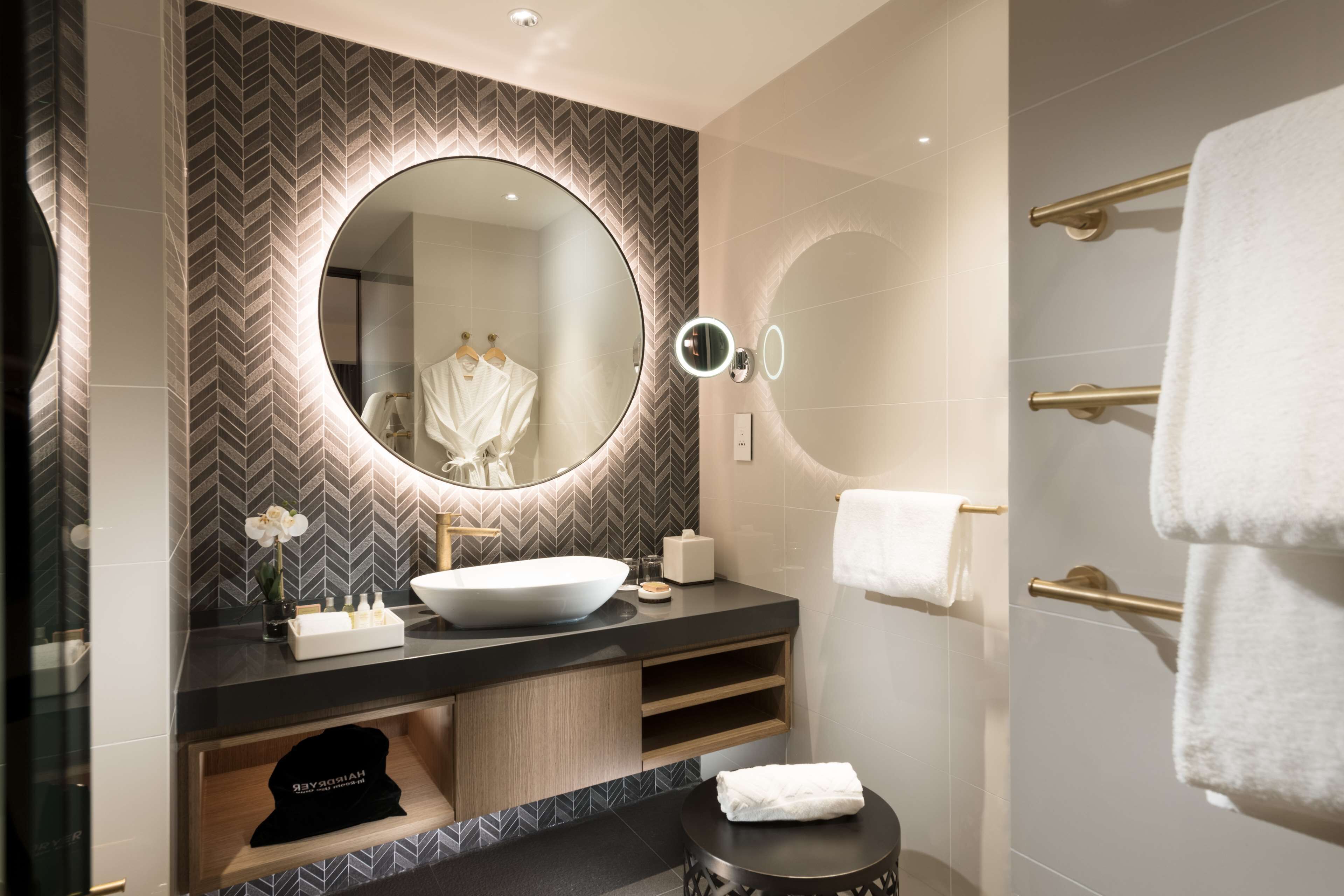 A modern bathroom with a large mirror, a vessel sink, and a towel rack.