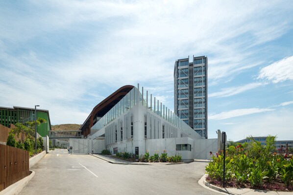 A modern building with a curved roof and a tall adjacent skyscraper.
