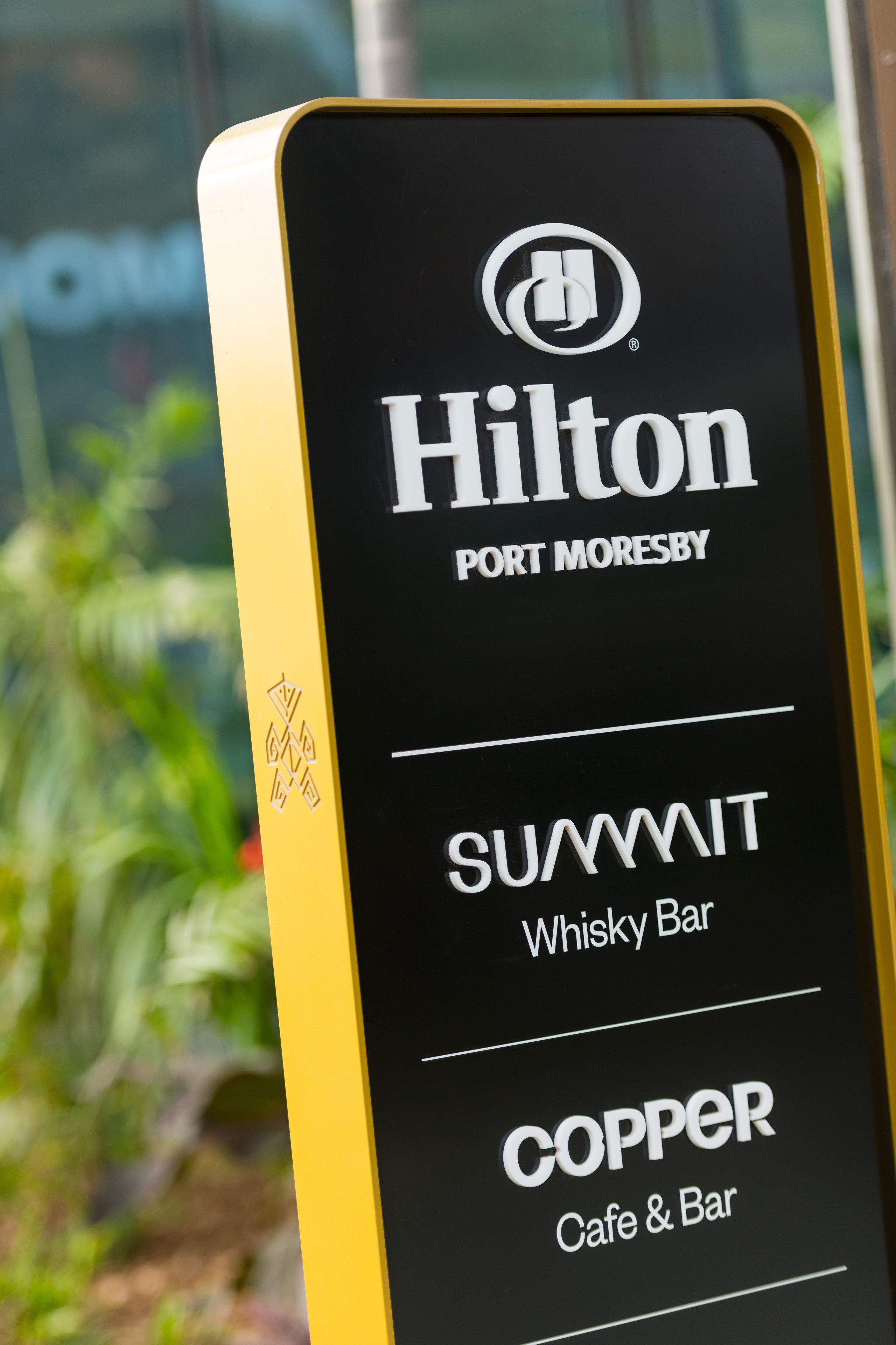 A sign for Hilton Port Moresby with the names of two bars: SUAMMIT Whisky Bar and COPPER Cafe & Bar.