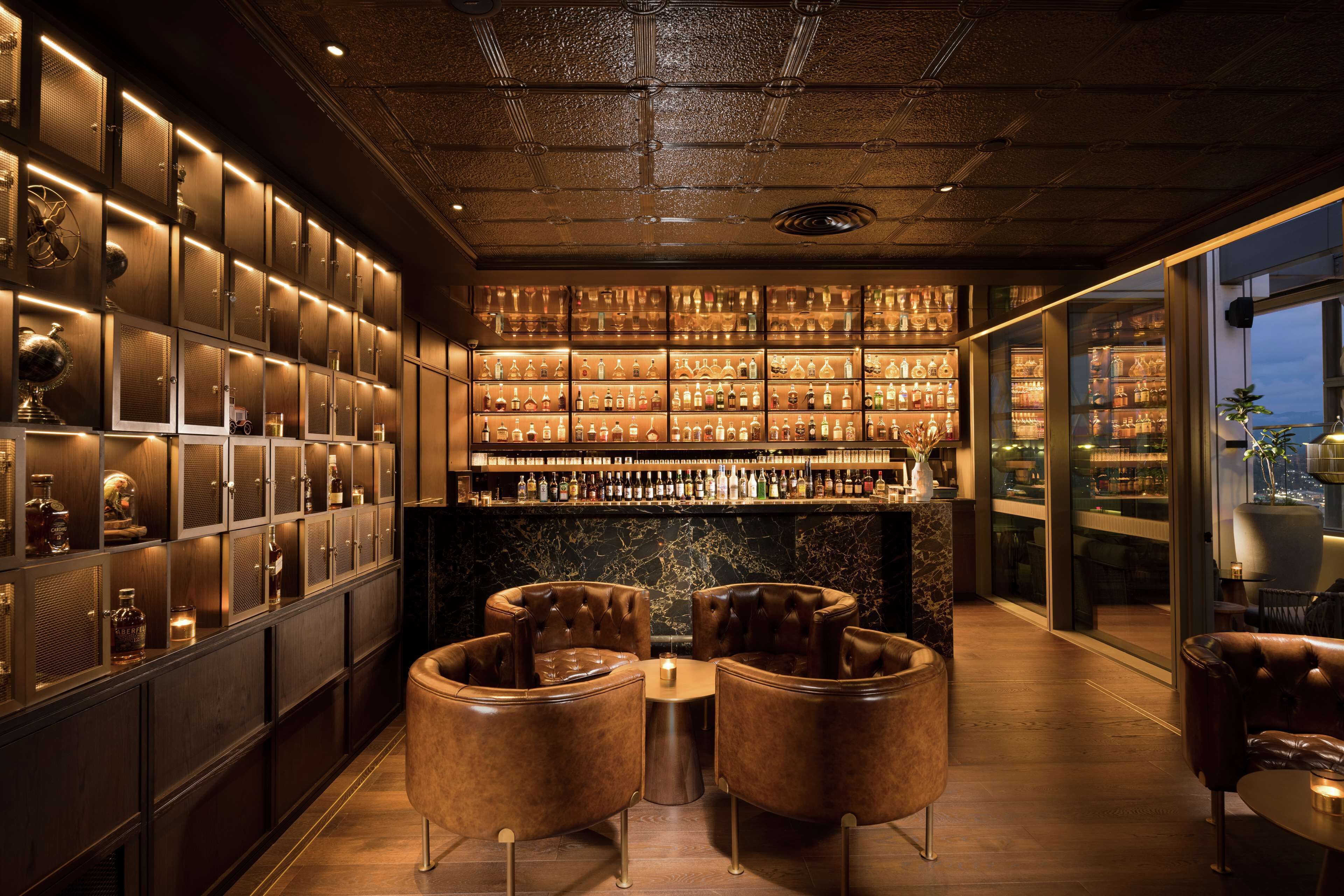 Un espace bar avec un décor intérieur en bois foncé, des sièges en cuir et un comptoir en marbre.