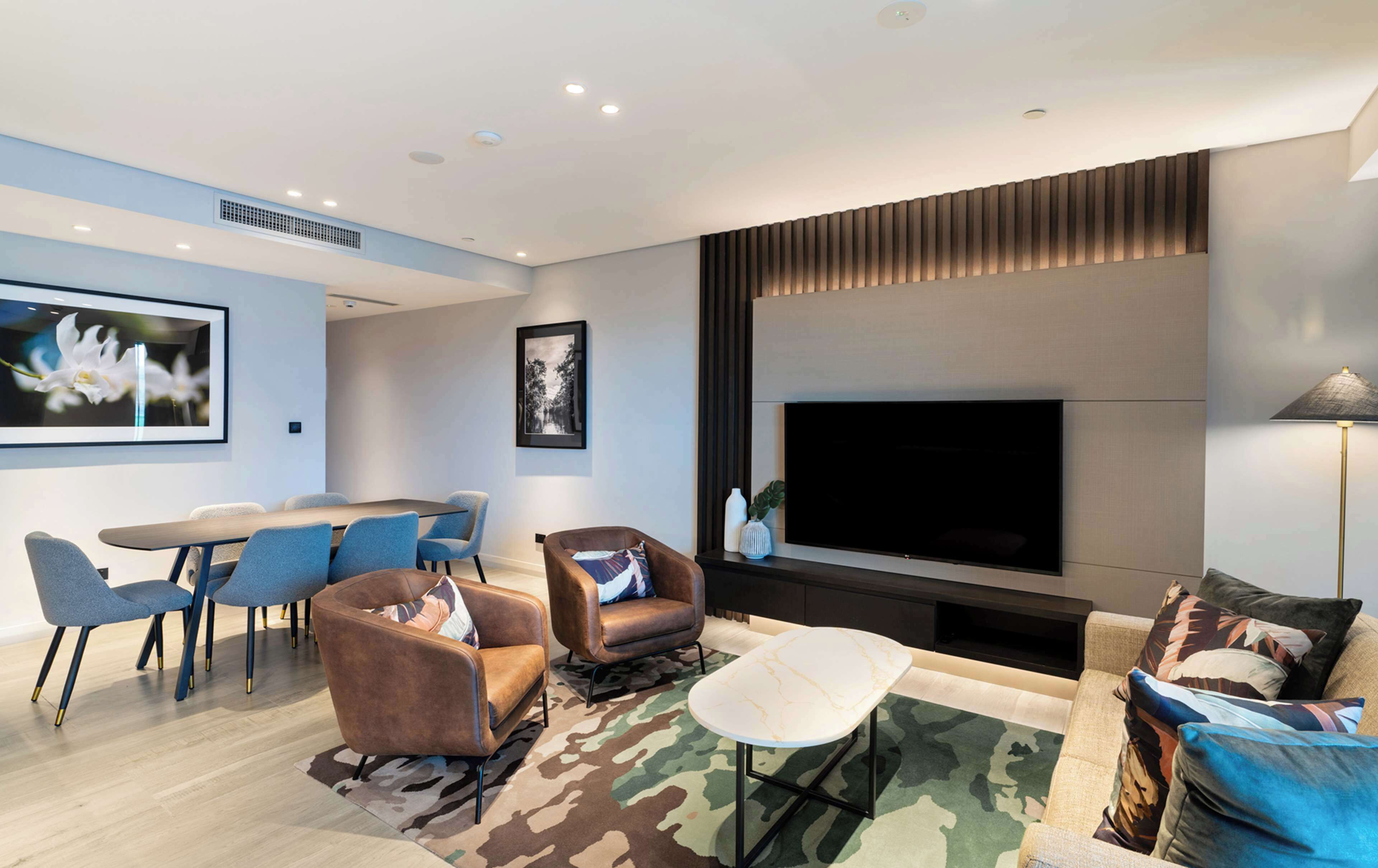 Una sala de estar moderna con un televisor de pantalla plana, asientos cómodos y un comedor.
