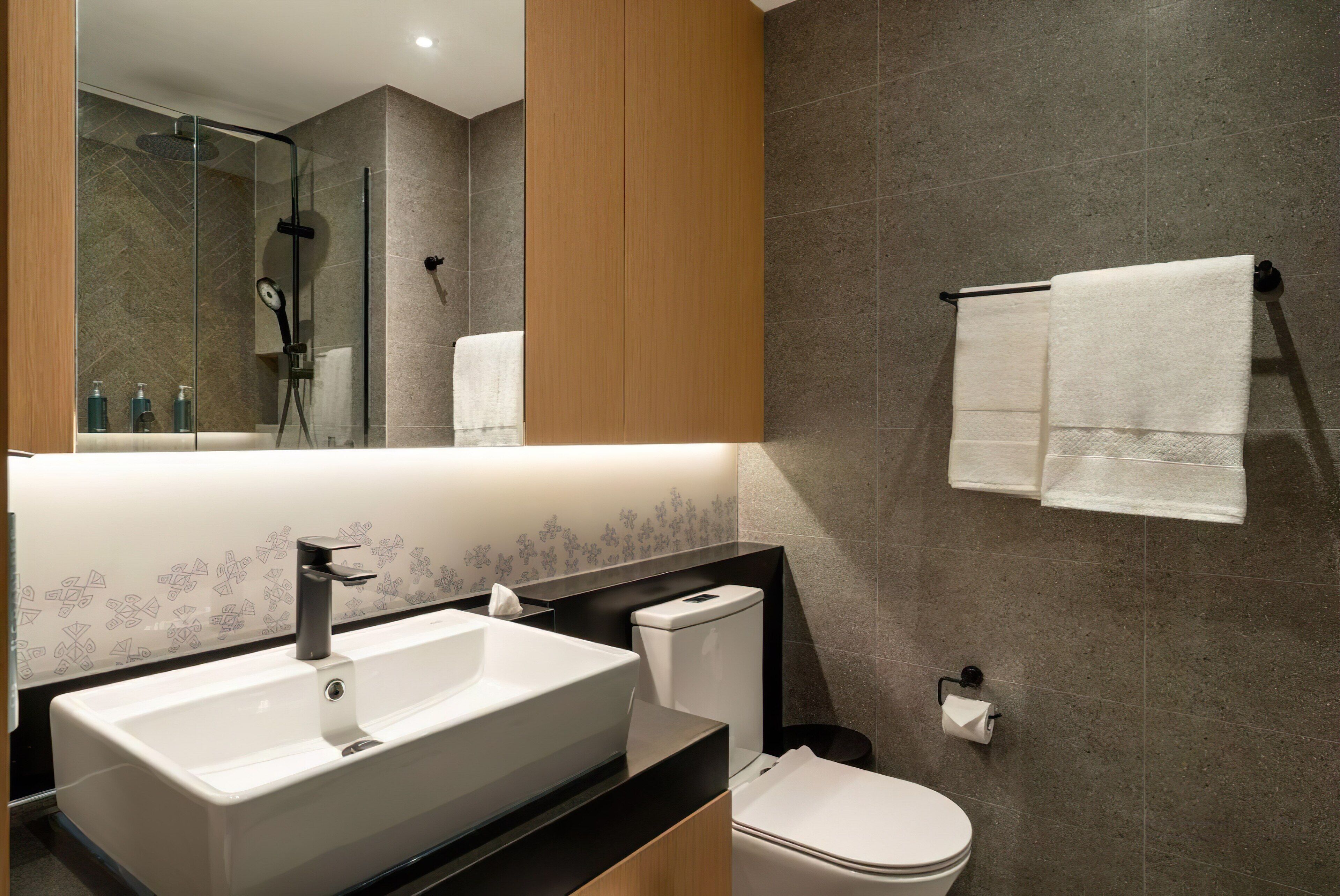 Une salle de bain moderne avec un grand lavabo, des toilettes et une douche à parois de verre.