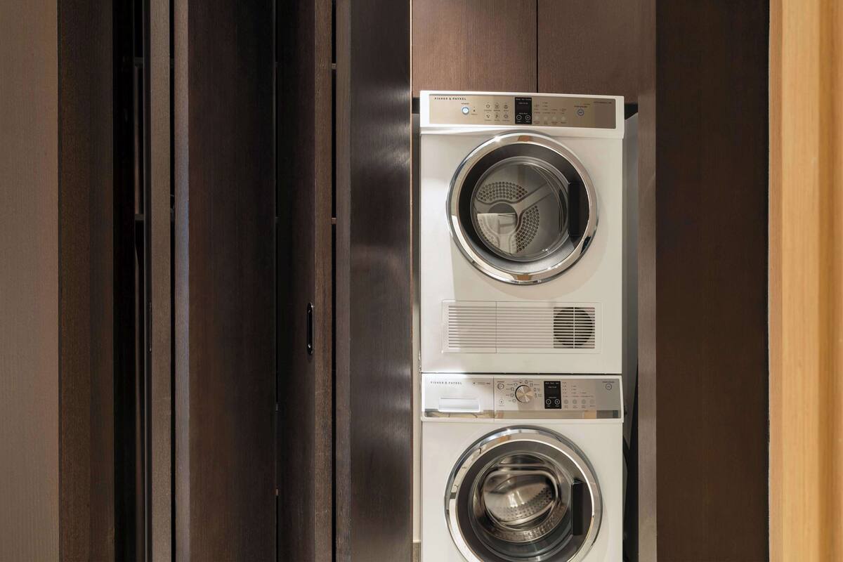 Een Fisher & Paykel was- en droogcombinatie met bedieningspaneel en een roestvrijstalen deur.