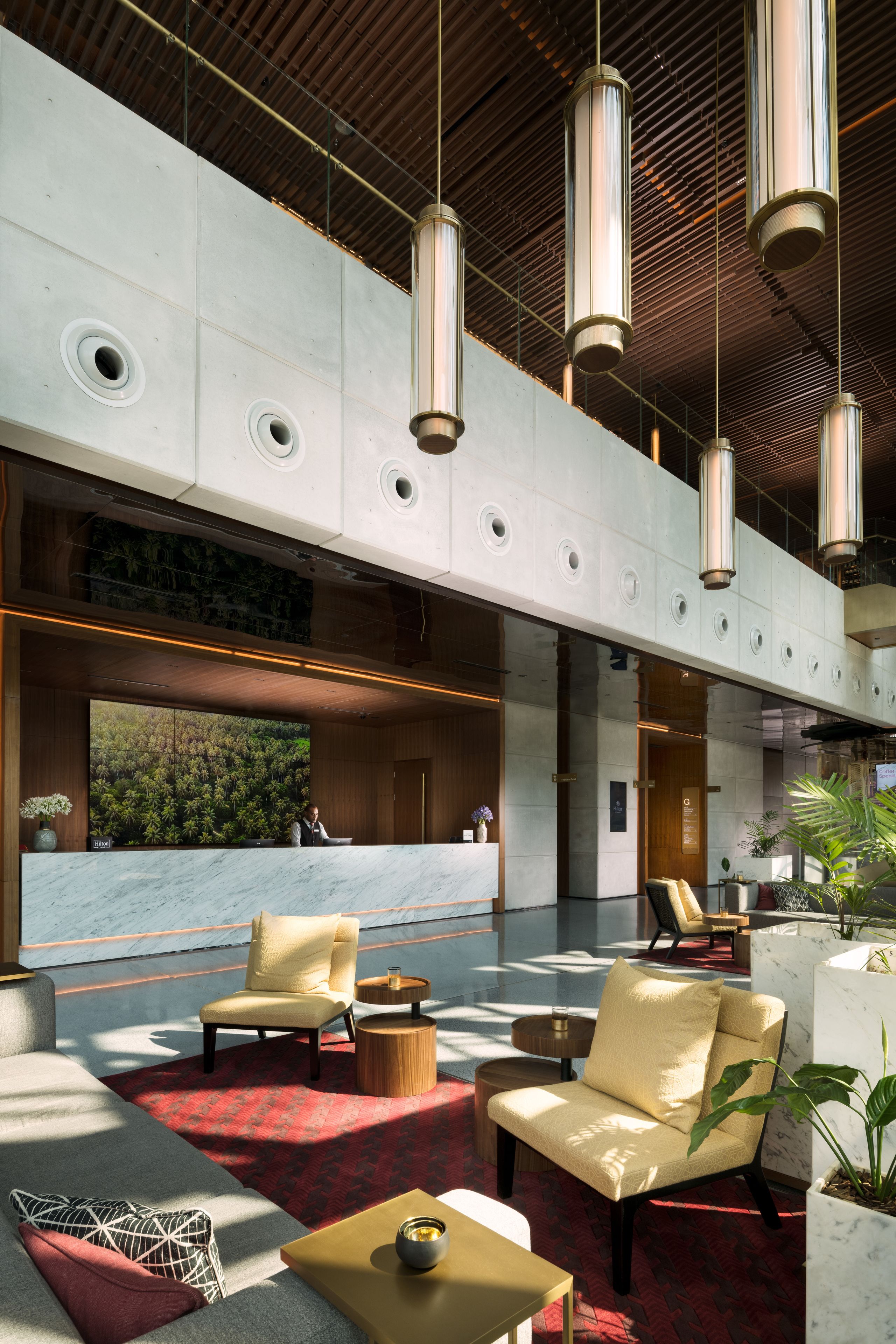 Eine moderne Lobby mit hoher Decke, großen Fenstern und einer Rezeption.