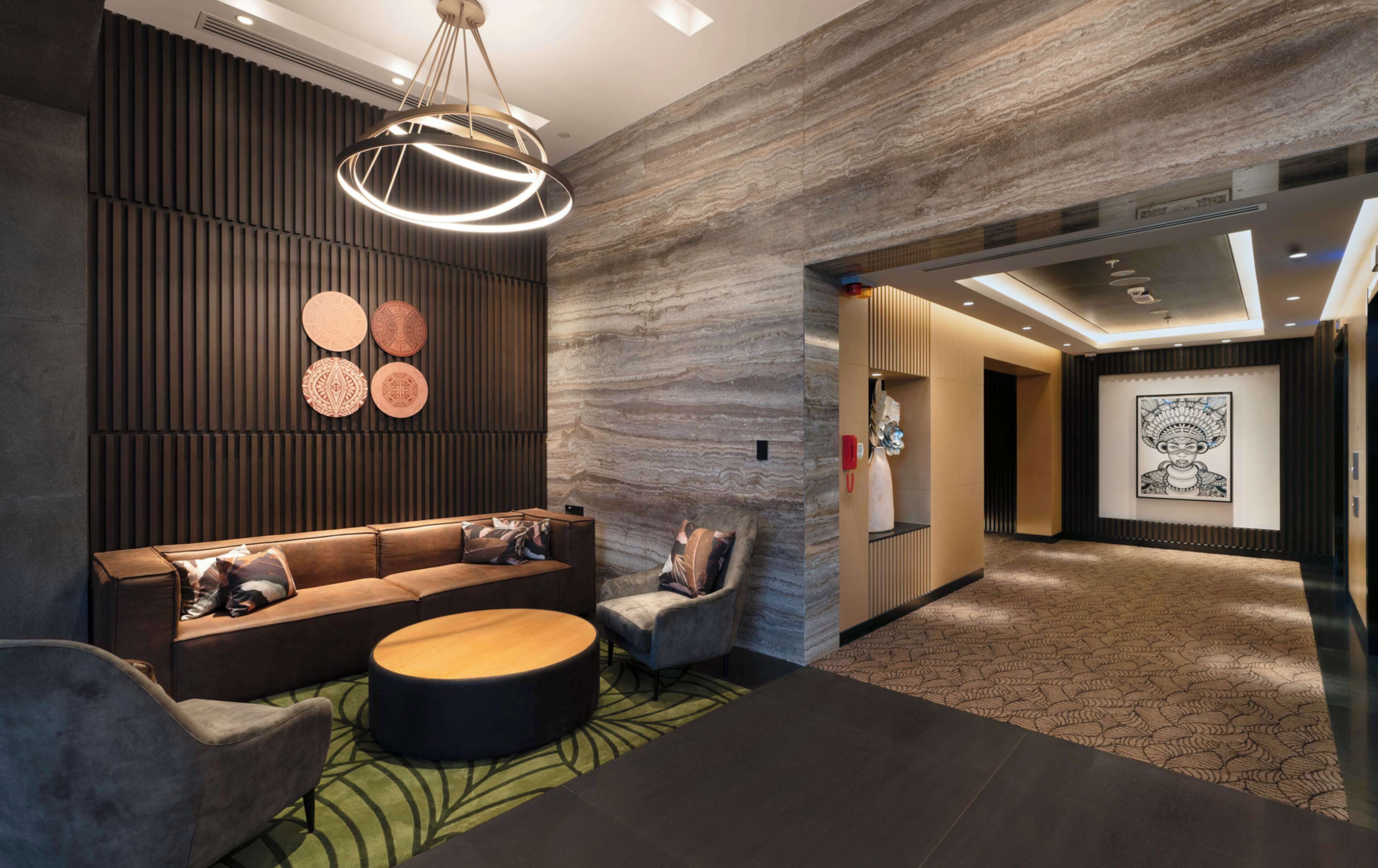 A modern lobby with a sectional sofa, a round coffee table, and a patterned carpet.