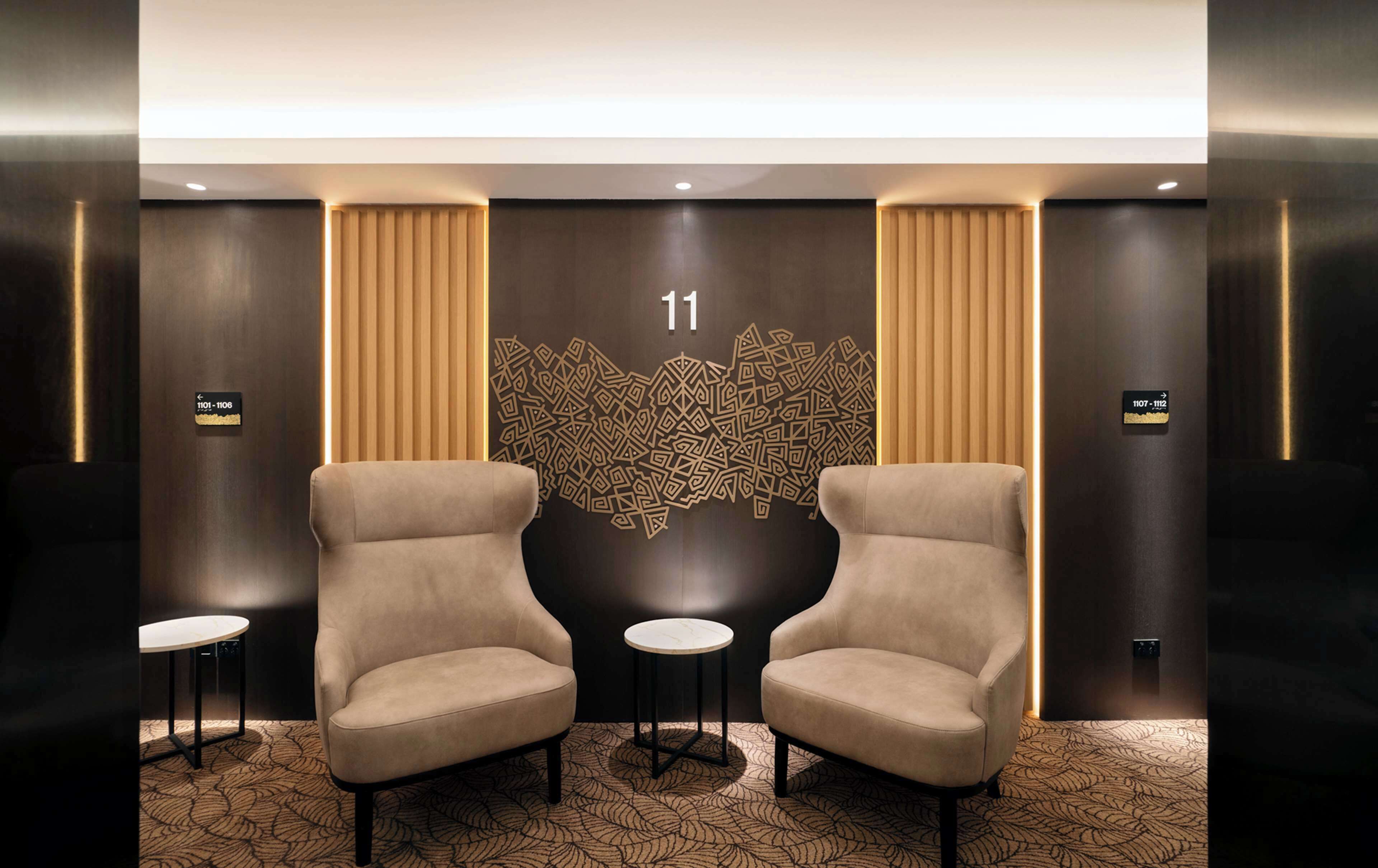 A modern lobby with two armchairs, a decorative wall with a geometric pattern, and a number '11' sign.