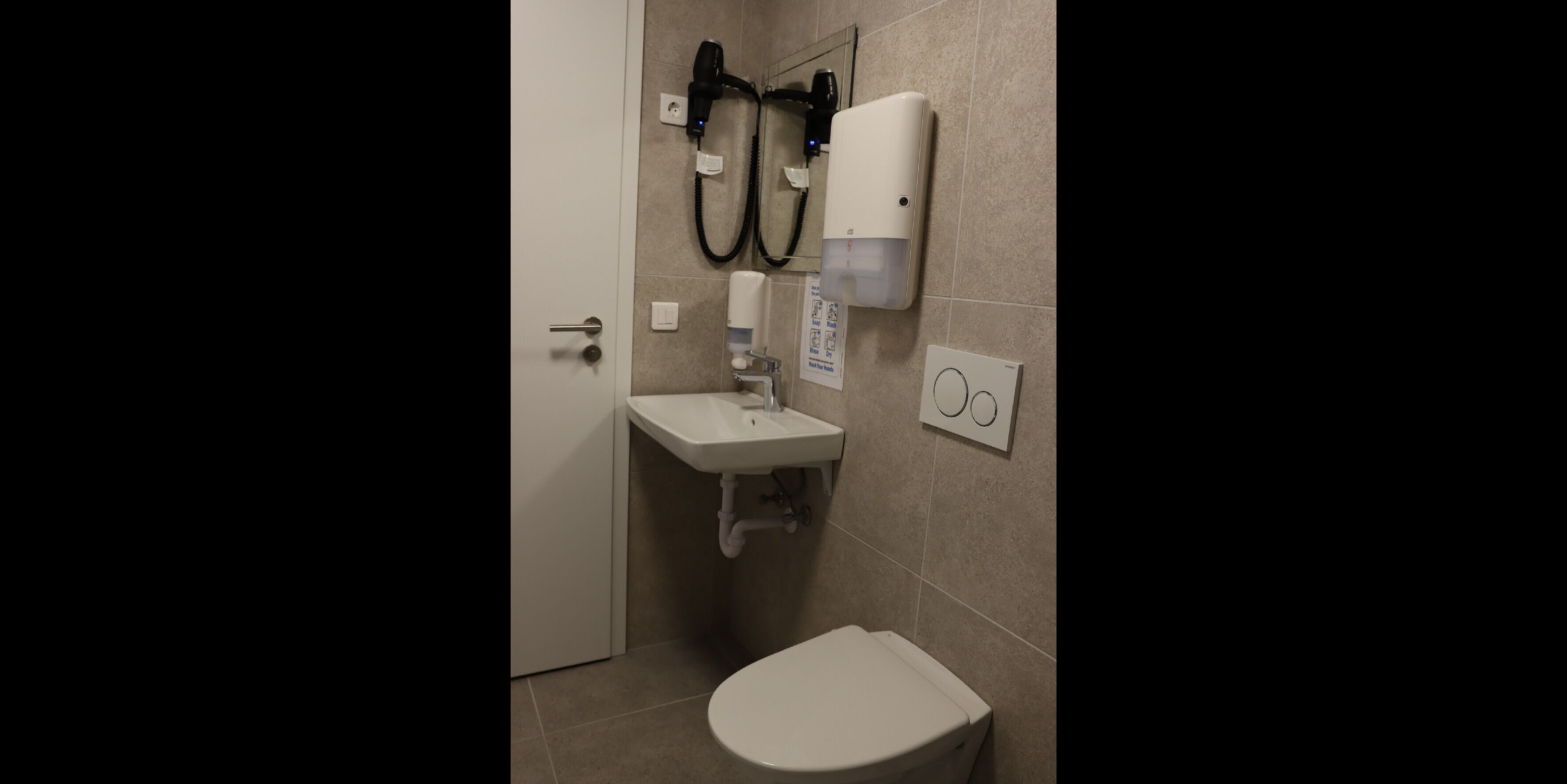 A small bathroom with a toilet, sink, and hand dryer.