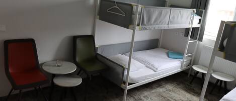 A bunk bed with a desk and chair, a small round table, and a mirror.