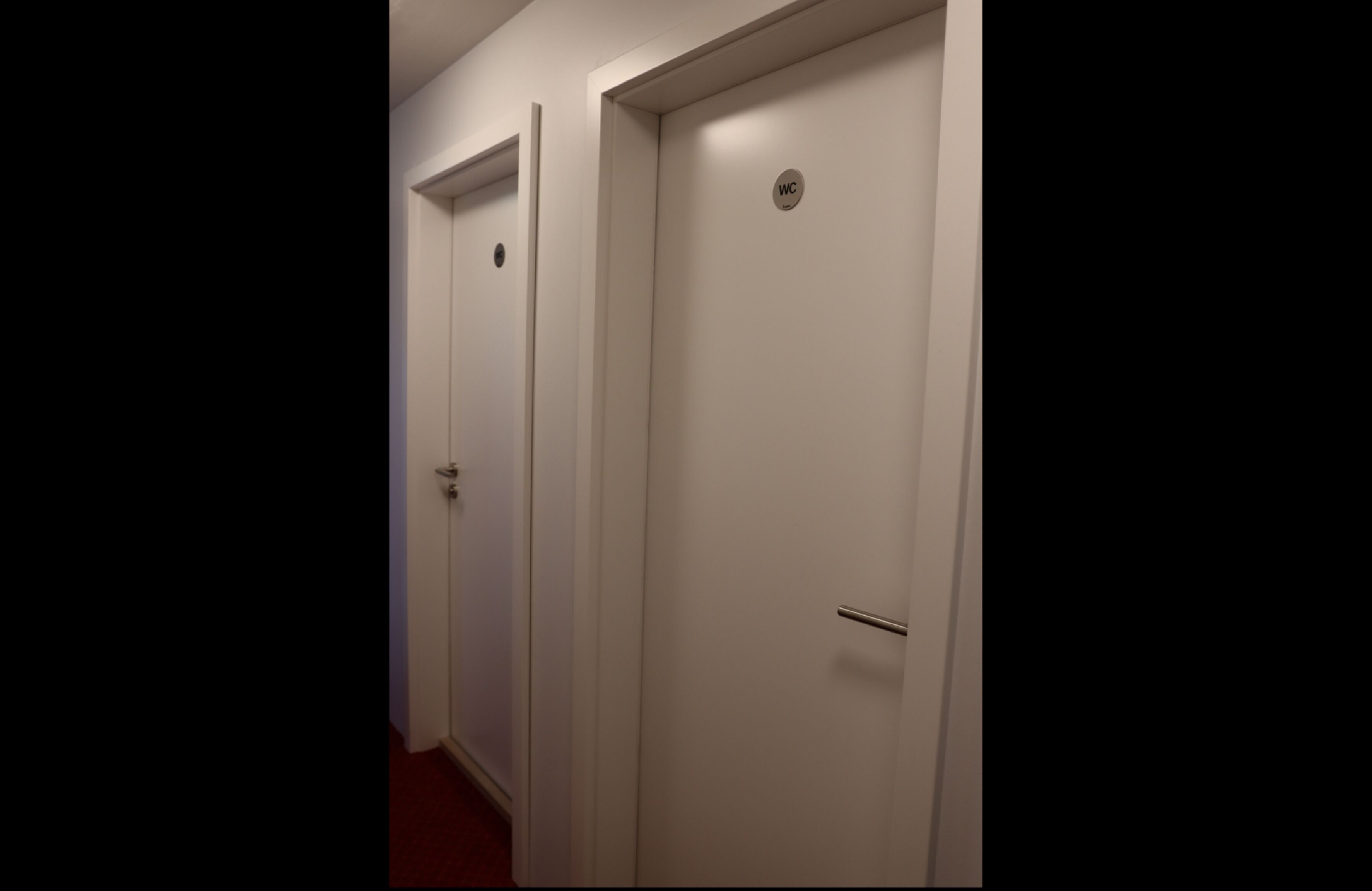 A hallway with two white doors, one marked with a "WC" sign.