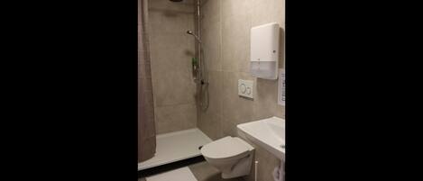 Un baño con ducha, inodoro y lavamanos.