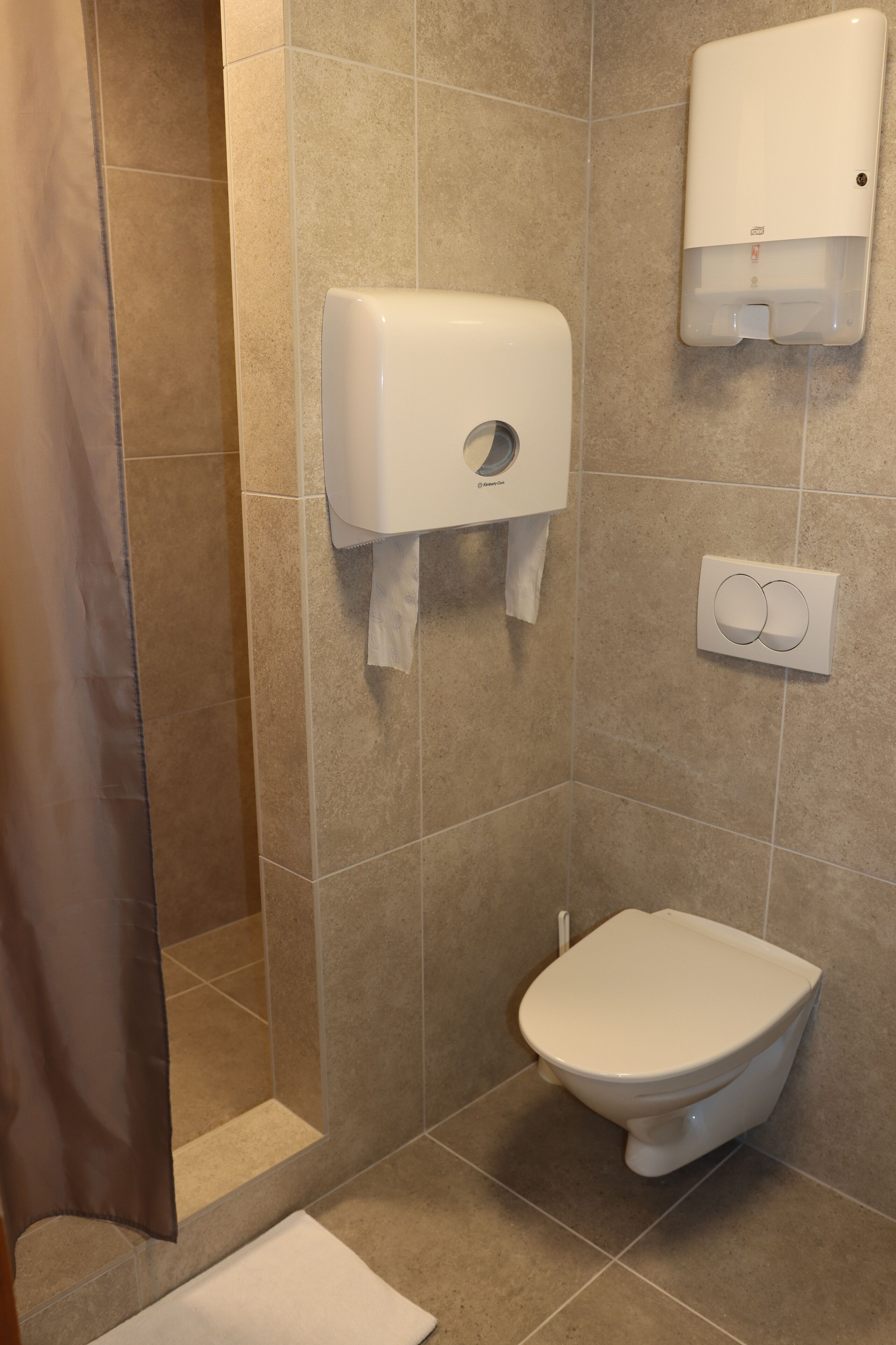 Une salle de bain équipée de toilettes, d’un distributeur d’essuie-tout et d’un distributeur de savon mural.