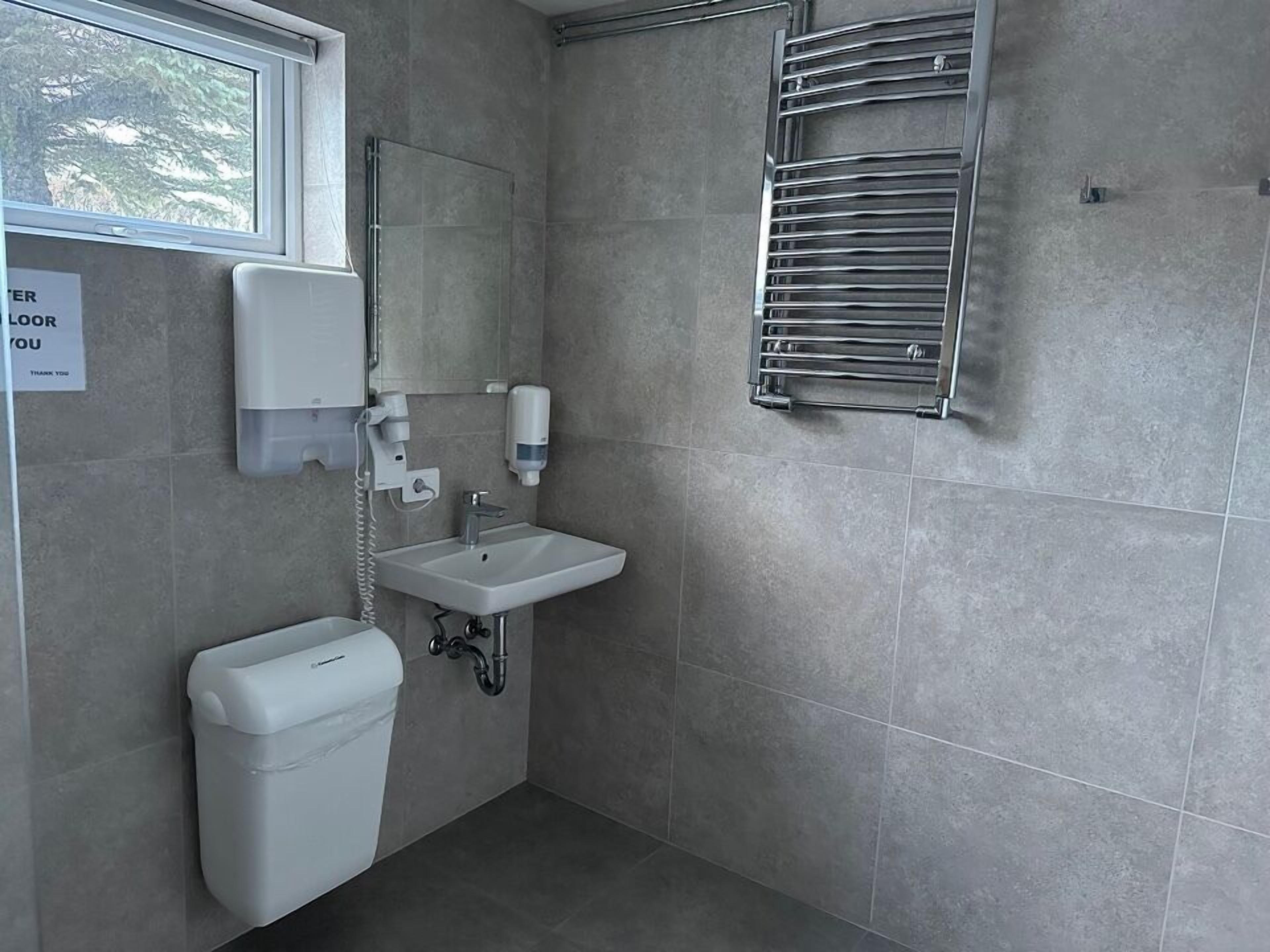 Un baño moderno con inodoro, lavamanos y toallero.