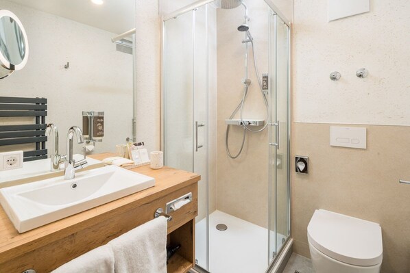 Une salle de bain moderne avec un meuble-lavabo en bois, un grand miroir, une cabine de douche et des toilettes.