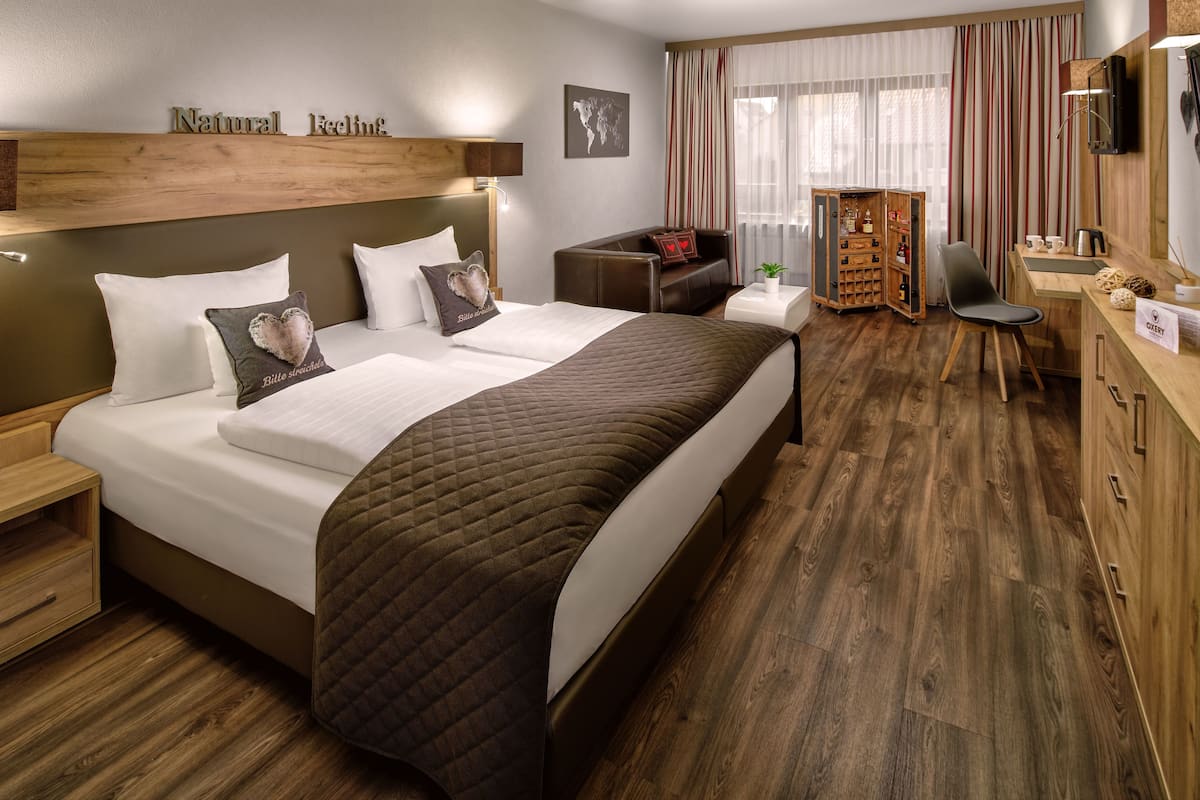 Une chambre d’hôtel avec un grand lit, un bureau, une chaise, une armoire et une vue sur l’extérieur.