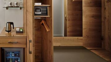 Habitación compacta y moderna con decoración de madera, minibar con bebidas, microondas y un pequeño rincón de descanso.
