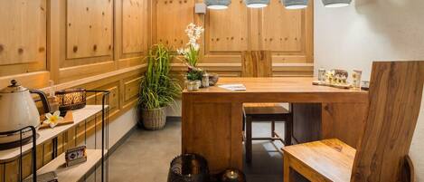 Un comedor de madera con una mesa, sillas, luces colgantes y una planta en maceta.