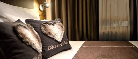 Una habitación de hotel con una cama bien hecha, un cojín con forma de corazón y un cojín con texto.