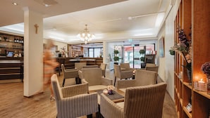 A hotel lobby with striped chairs, a reception desk, a chandelier, and a bar area. - Kurhotel Panland (Bad Fuessing)