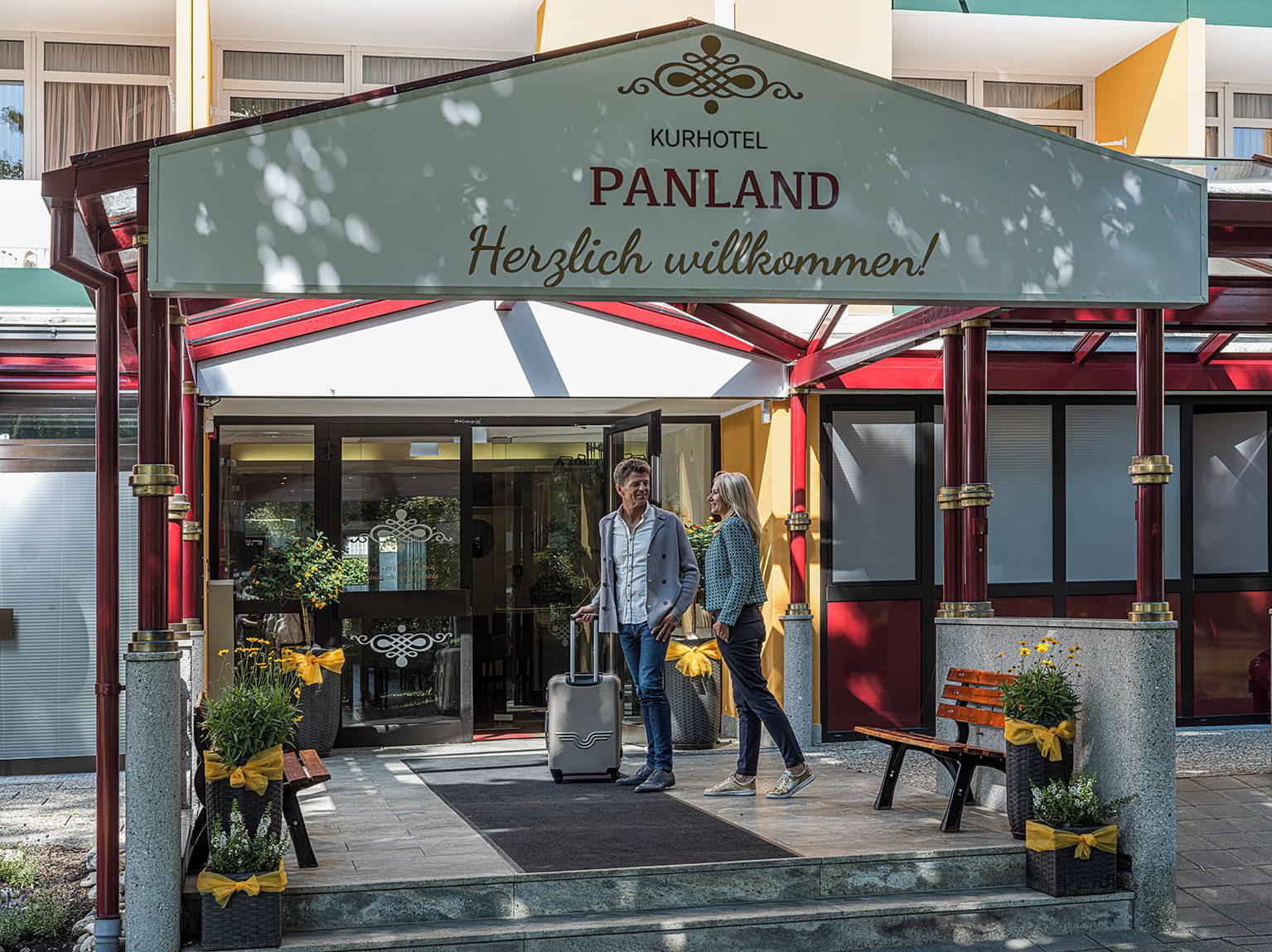 Entrada de un hotel con un cartel que dice "Kurhotel Panland" y "¡Bienvenido!"
