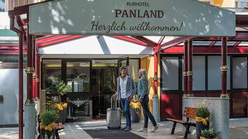 Entrada de un hotel con un cartel que dice "Kurhotel Panland" y "¡Bienvenido!"