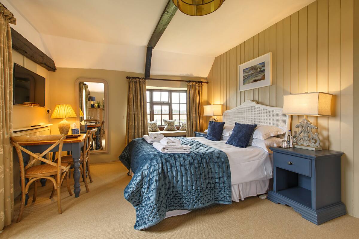 A bedroom with a large bed, bedside tables, a desk, and a chair.