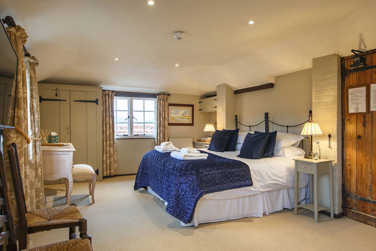 A bedroom with a large bed, bedside tables, a chair, and a window.