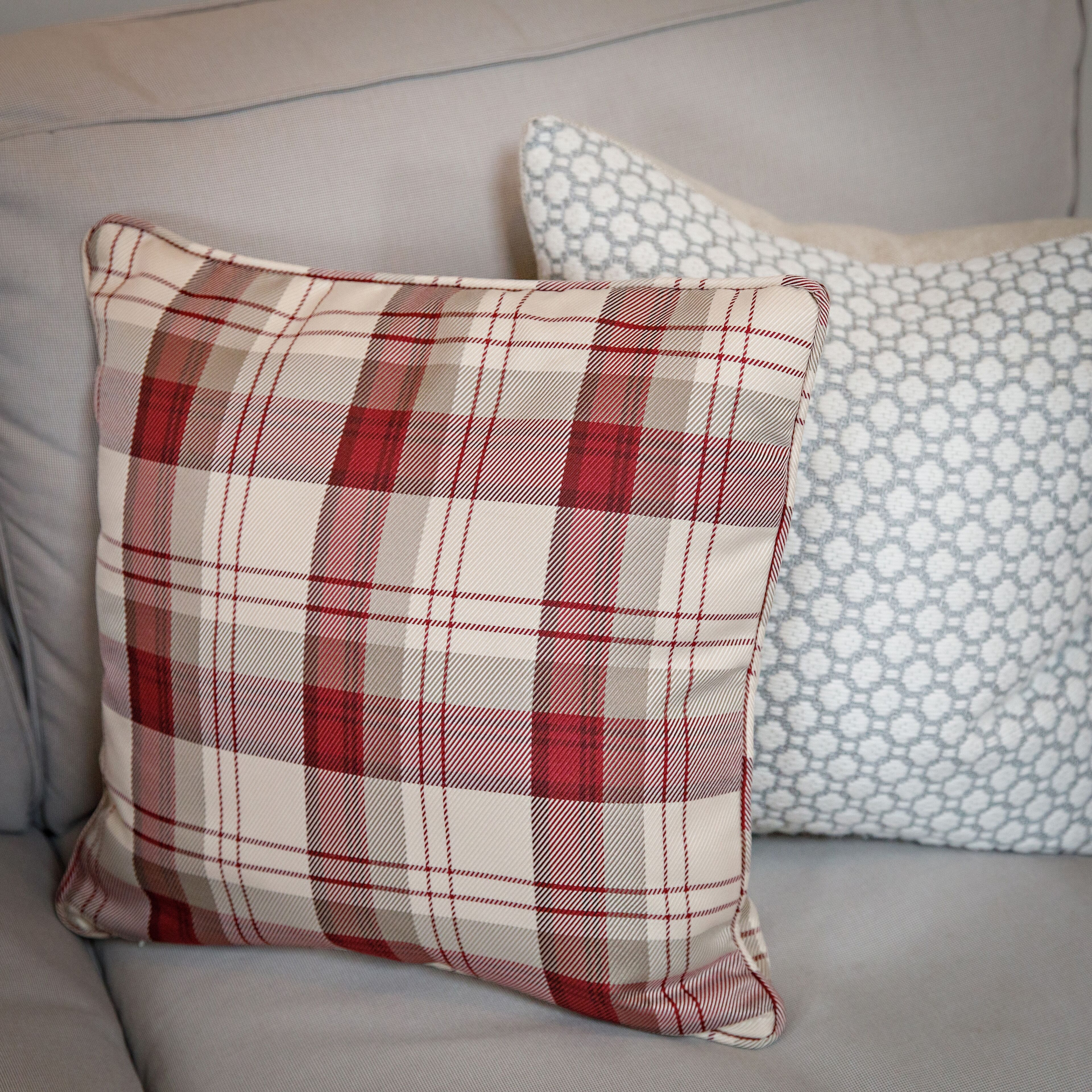 A sofa with two pillows, one with a plaid pattern and the other with a geometric design.