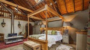 A rustic bedroom with a four-poster bed, wooden furniture, a stone fireplace, and a stone floor. - Cley Windmill (Holt)