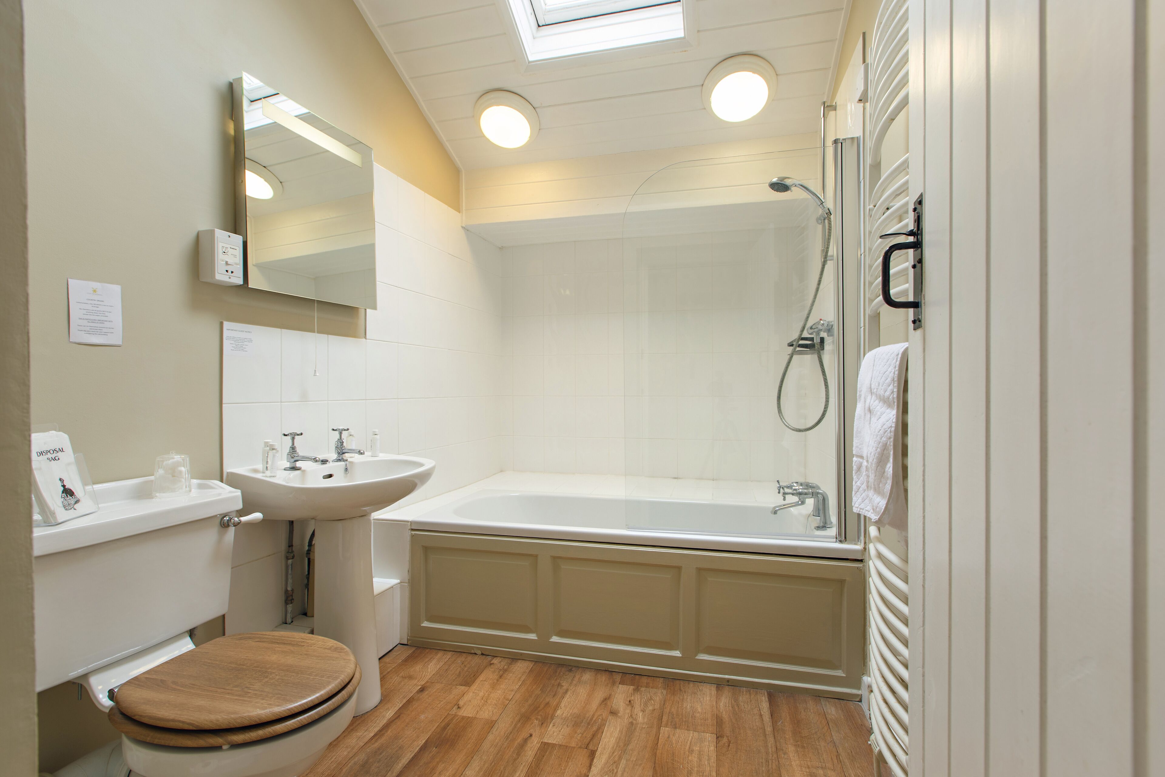 A bathroom with a wooden toilet, a sink, a mirror, a bathtub, and a shower.