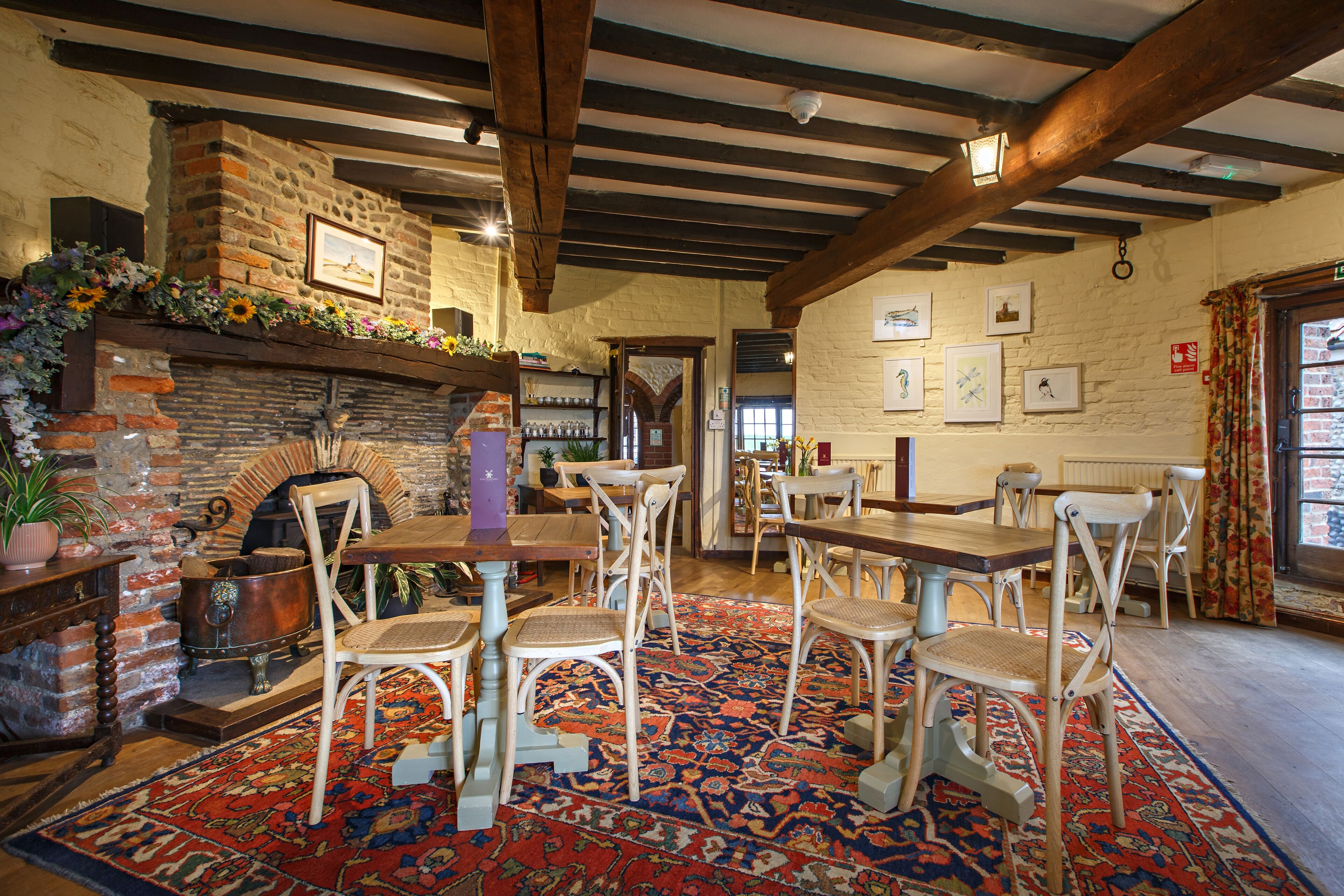 Une pièce rustique avec une cheminée en pierre, des poutres en bois et un tapis à motifs.
