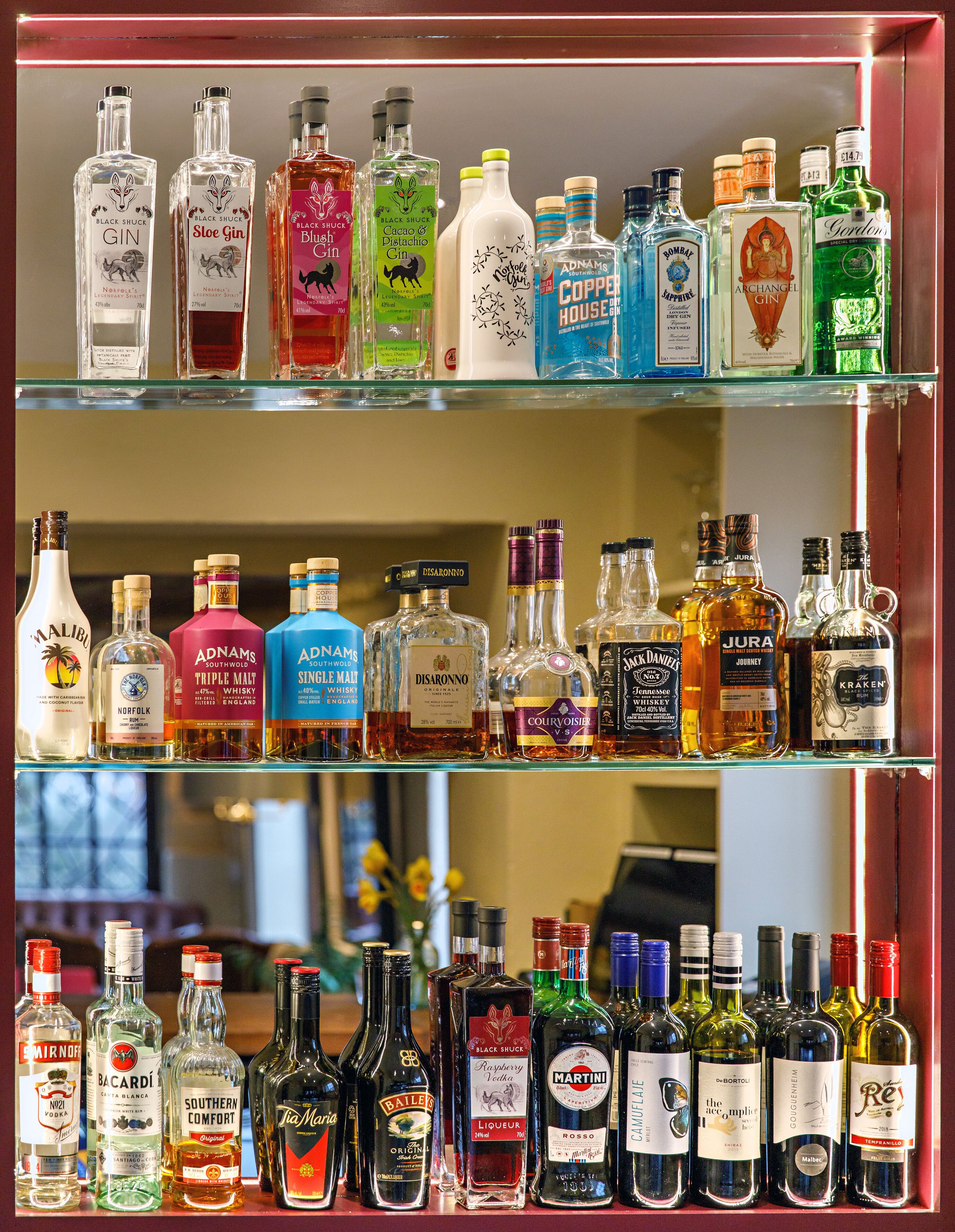 A liquor store shelf with various bottles of gin, whiskey, and other spirits.