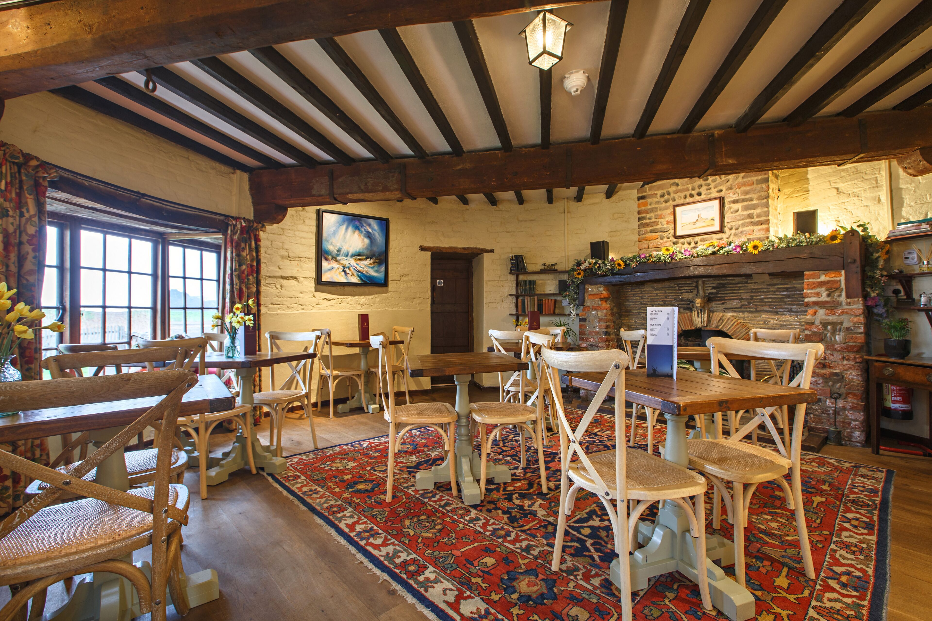 A rustic interior with wooden furniture, a patterned rug, and a brick fireplace.