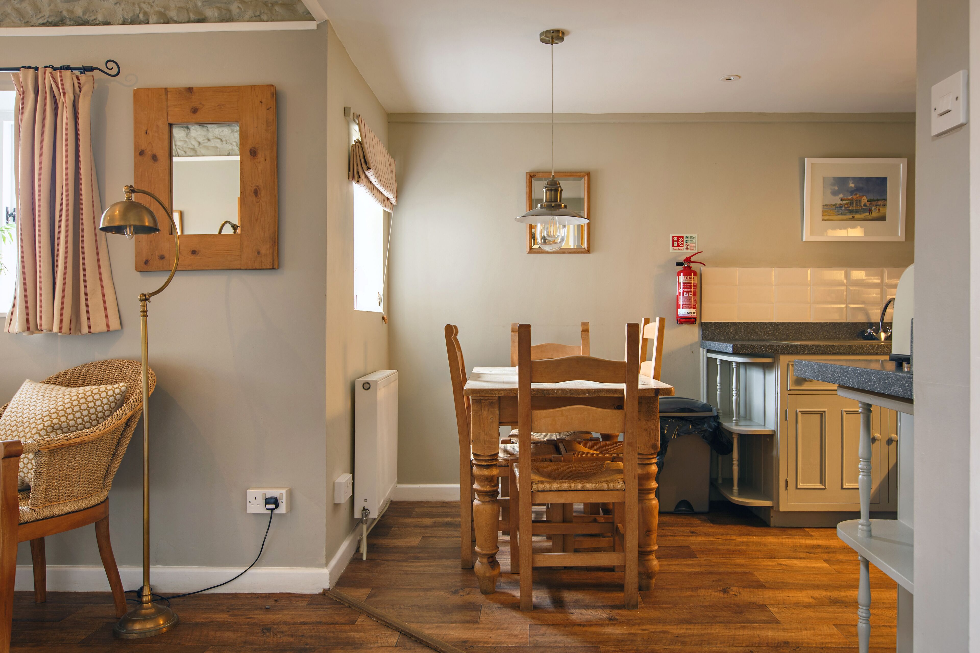 A dining area with a wooden table and chairs, a floor lamp, and a mirror on the wall.